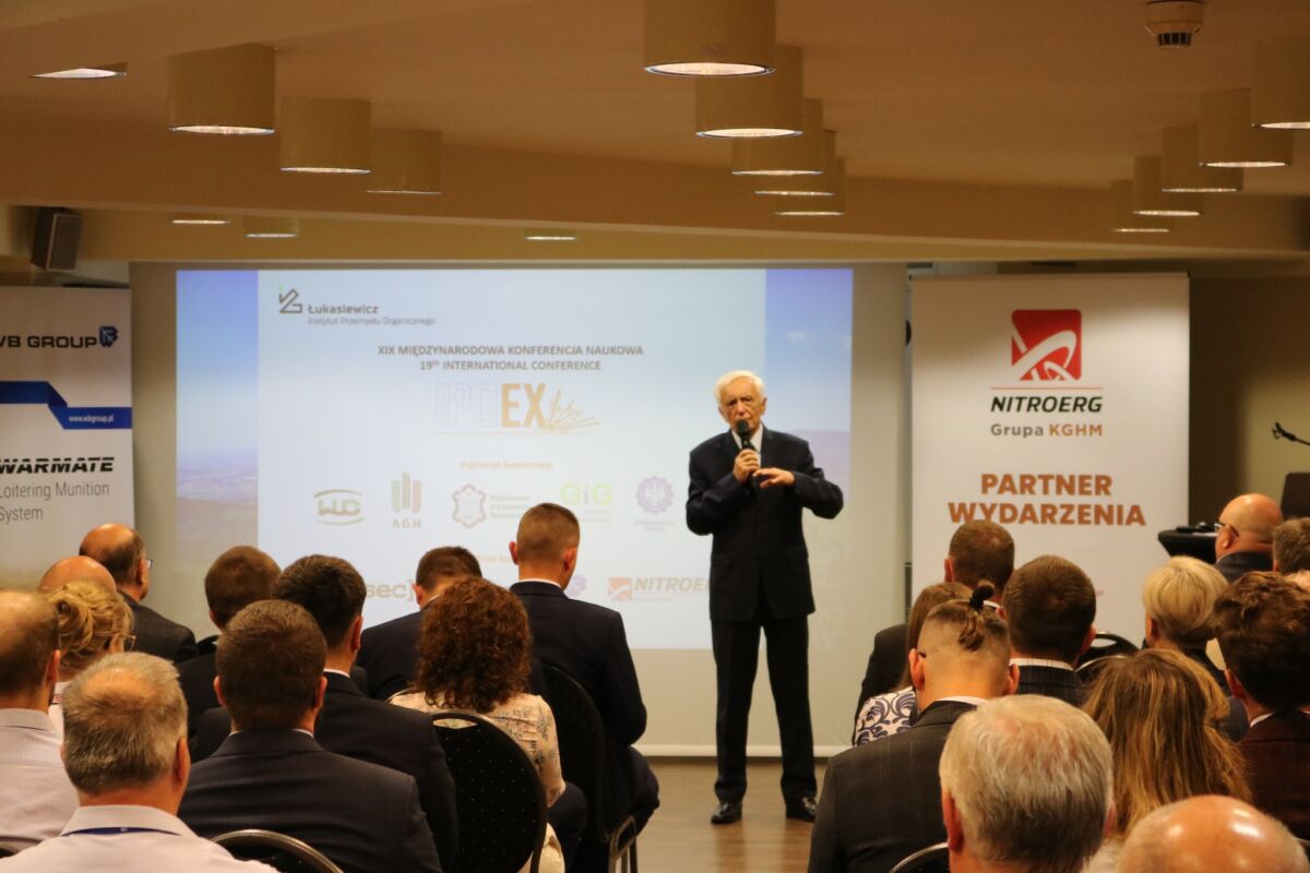 Zdjęcie przedstawia mężczyznę  mówiącego do grupy ludzi na sali konferencyjnej