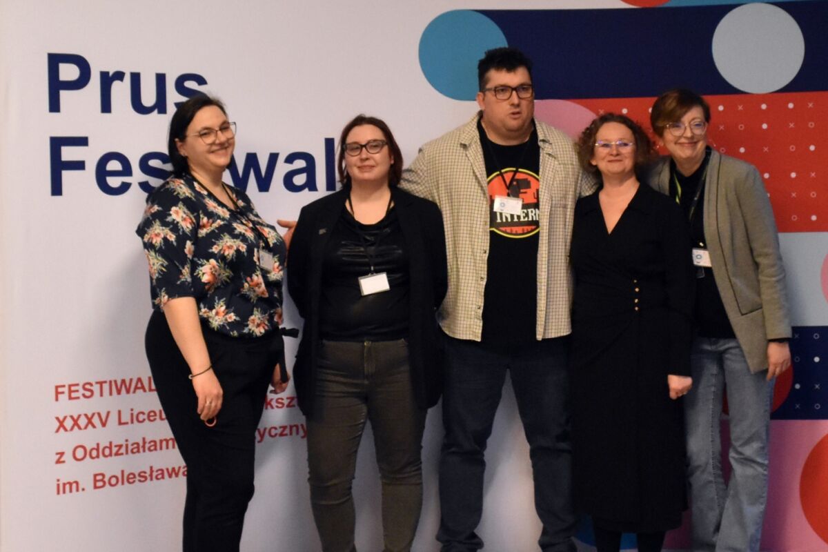 Zdjęcie przedstawiające pieć osób pozujących na tle banneru Festiwalu Nauki w Prusie